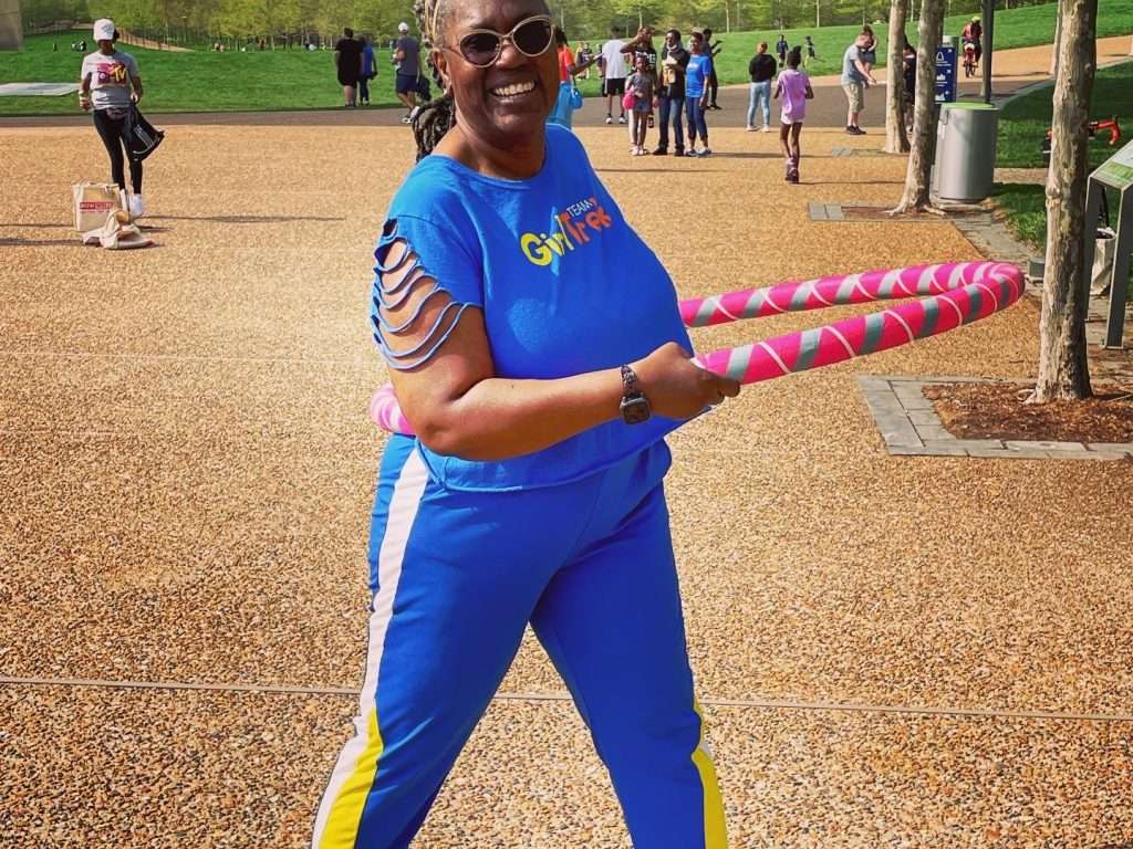 Woman on playground smiling, playing with hula hoop